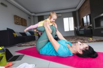Kaukasische Mutter hält ihr Baby und macht zu Hause Yoga. Mutterschaft, Liebe und Babypflege-Konzept — Stockfoto