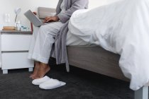 Жінка сидить на ліжку за допомогою ноутбука. перебування вдома в ізоляції під час карантину . — стокове фото