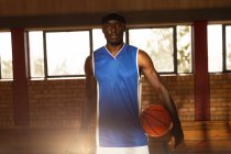 Ritratto di giocatore di basket afro-americano con palla in mano. pallacanestro, allenamento sportivo in un campo coperto. — Foto stock