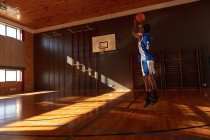 Jugador de baloncesto masculino de raza mixta practicando tiro con pelota. baloncesto, entrenamiento deportivo en una cancha cubierta. - foto de stock