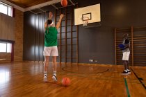 Jugadora de baloncesto caucásica y entrenadora practicando tiro con pelota. baloncesto, entrenamiento deportivo en una cancha cubierta. - foto de stock