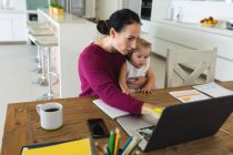 Mãe branca segurando seu bebê usando laptop enquanto trabalhava em casa. maternidade, amor e conceito de cuidado do bebê — Fotografia de Stock