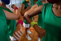 Разнообразная женская баскетбольная команда в масках и приветствиях с локтями. баскетбол, спортивные тренировки на крытом корте во время пандемии коронавируса. — стоковое фото