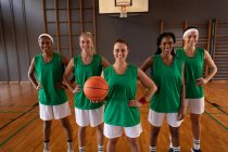 Портрет разнообразной женской баскетбольной команды, носящей спортивную одежду и улыбающейся. баскетбол, спортивные тренировки на крытой площадке. — стоковое фото