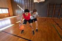 Dos diversos jugadores de baloncesto practican driblando. baloncesto, entrenamiento deportivo en una cancha cubierta. - foto de stock