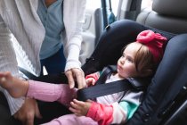 In der Mitte einer Mutter, die ihr Baby in einen sicheren Kindersitz im Auto legt. Mutterschaft, Liebe und Babypflege-Konzept — Stockfoto