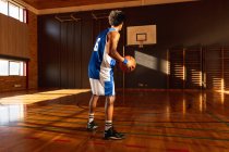 Jogador de basquete masculino de raça mista praticando tiro com bola. basquete, treinamento esportivo em uma quadra interna. — Fotografia de Stock