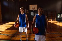 Porträt zweier unterschiedlicher männlicher Basketballspieler mit Bällen. Basketball, Sporttraining auf einem Indoor-Court. — Stockfoto