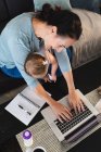 Sorrindo mãe caucasiana segurando seu bebê usando laptop enquanto trabalhava em casa. maternidade, amor e conceito de cuidado do bebê — Fotografia de Stock