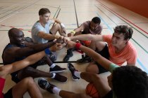 Equipe de basquete masculino diverso e treinador descansando após o jogo e se unindo. basquete, treinamento esportivo em uma quadra interna. — Fotografia de Stock