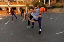 Equipe de basquete feminina diversa vestindo roupas esportivas e praticar driblando bola. basquete, treinamento esportivo em um campo urbano ao ar livre. — Fotografia de Stock