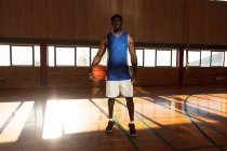 Retrato de un jugador de baloncesto afroamericano que sostiene la pelota. baloncesto, entrenamiento deportivo en una cancha cubierta. - foto de stock