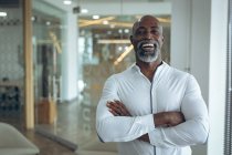 Porträt eines afrikanisch-amerikanischen Geschäftsmannes, der mit verschränkten Armen in die Kamera blickt. Arbeit in einem unabhängigen kreativen Unternehmen. — Stockfoto