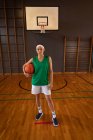 Retrato de una jugadora de baloncesto caucásica sosteniendo la pelota. baloncesto, entrenamiento deportivo en una cancha cubierta. - foto de stock