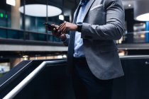 Seção média do homem de negócios usando smartphone em pé perto das escadas no escritório. conceito de negócio e escritório — Fotografia de Stock