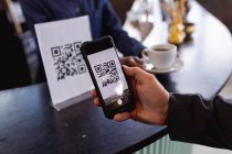 Mid section of man making a payment by scanning qr code from smartphone at a cafe. digital and cashless payment technology concept — Stock Photo