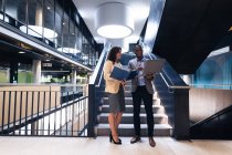 Homme d'affaires divers et femme d'affaires discutant ensemble debout près des escaliers au bureau. concept d'entreprise et de bureau — Photo de stock