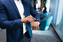 Parte média do homem de negócios usando smartwatch no escritório moderno. conceito de negócio e escritório — Fotografia de Stock