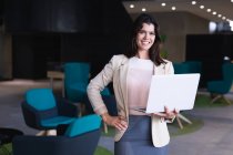 Retrato de mulher de negócios caucasiana segurando um laptop sorrindo enquanto estava no escritório moderno. conceito de negócio e escritório — Fotografia de Stock