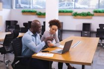 Два разных коллеги по бизнесу мужчины и женщины сидят за столом, используют ноутбук и обсуждают. работа в независимом креативном бизнесе. — стоковое фото
