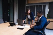 Различные бизнесмен и деловая женщина обсуждают за ноутбуком в конференц-зале в современном офисе. бизнес и офисная концепция — стоковое фото