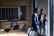 Разнообразный бизнесмен и деловая женщина обсуждают за цифровым планшетом в конференц-зале в офисе. бизнес и офисная концепция — стоковое фото