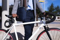 Parte média do empresário com bicicleta em pé no parque corporativo. conceito de negócio e escritório — Fotografia de Stock