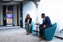 Различные бизнесмен и деловая женщина обсуждают вместе, сидя в современном офисе. бизнес и офисная концепция — стоковое фото