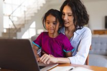 Усміхаючись іспаномовній матері і доньці, сидячи у вітальні, використовуючи ноутбук разом. сім'я проводить час разом вдома . — стокове фото