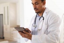 Der hispanische Arzt im Laborkittel konzentriert sich mit einem digitalen Tablet. Medizin- und Gesundheitstechnologie. — Stockfoto