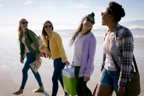 Grupo feliz de amigas divertidas se divertindo, andando ao longo da praia e rindo. férias, liberdade e lazer ao ar livre. — Fotografia de Stock