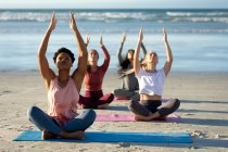 Gruppo di diverse amiche che praticano yoga, meditando in spiaggia. sano stile di vita attivo, fitness e benessere all'aperto. — Foto stock
