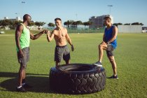 Diverse fröhliche Männer ohne Hemd trainieren im Freien, machen eine Pause und schlagen mit den Fäusten. gesunder aktiver Lebensstil, Crosstraining für Fitness. — Stockfoto