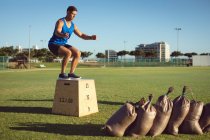 Fit homme caucasien exercice en plein air sautant sur la boîte. mode de vie sain et actif, entraînement croisé pour la forme physique. — Photo de stock