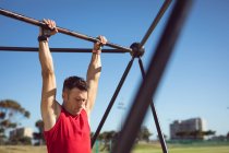 Kaukasischer muskulöser Mann, der im Freien an einem Trainingsgestell hängt. gesunder aktiver Lebensstil, Crosstraining für Fitness. — Stockfoto