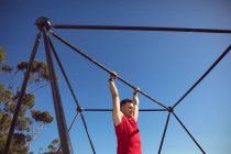 Caucásico hombre musculoso colgando en el marco de ejercicio al aire libre. estilo de vida activo saludable, entrenamiento cruzado para fitness. - foto de stock