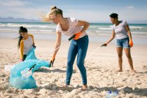 Diverso gruppo di donne che camminano lungo la spiaggia, raccogliendo spazzatura. volontari per la conservazione dell'ambiente, pulizia della spiaggia. — Foto stock