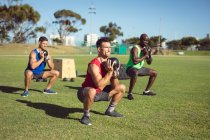 Diverso grupo de hombres musculosos haciendo ejercicio con campanas al aire libre. estilo de vida activo saludable, entrenamiento cruzado para el concepto de fitness. - foto de stock