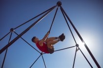 Caucasian muscular man hanging on exercise frame outdoors. healthy active lifestyle, cross training for fitness. — Stock Photo