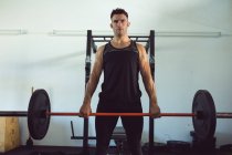 Retrato de homem caucasiano apto se exercitando no ginásio, levantando pesos na barra. estilo de vida ativo saudável, treinamento cruzado para fitness. — Fotografia de Stock