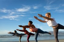 Gruppe verschiedener Freundinnen, die Yoga praktizieren, sich am Strand dehnen. gesunder aktiver Lebensstil, Fitness und Wohlbefinden im Freien. — Stockfoto