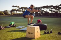 Fit homme caucasien exercice en plein air sautant sur la boîte. mode de vie sain et actif, entraînement croisé pour la forme physique. — Photo de stock