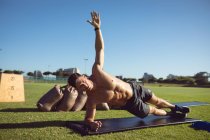 Homem musculoso caucasiano exercitando ao ar livre, fazendo prancha lateral. estilo de vida ativo saudável, treinamento cruzado para fitness. — Fotografia de Stock