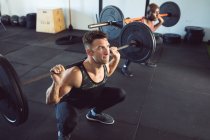 Un uomo caucasico in forma che fa ginnastica, che solleva pesi sul bilanciere. sano stile di vita attivo, cross training per il fitness. — Foto stock