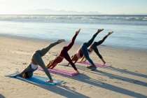 Gruppe verschiedener Freundinnen, die Yoga praktizieren, sich am Strand dehnen. gesunder aktiver Lebensstil, Fitness und Wohlbefinden im Freien. — Stockfoto