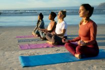 Група різноманітних друзів-жінок, які практикують йогу, медитують на пляжі. здоровий активний спосіб життя, фітнес на відкритому повітрі та благополуччя . — стокове фото