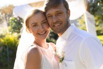 Portrait of happy caucasian bride and groom getting married and embracing. summer wedding, marriage, love and celebration concept. — Stock Photo