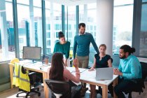 Eine Gruppe unterschiedlicher Geschäftsleute diskutiert gemeinsam am Tisch sitzend und mit Laptop. Arbeit in einem modernen Büro. — Stockfoto