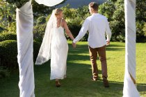 Glückliche kaukasische Braut und Bräutigam beim Heiraten Händchen haltend. Sommerhochzeit, Ehe, Liebe und Festkonzept. — Stockfoto
