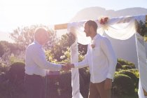 Kaukasischer Bräutigam heiratet und schüttelt dem Hochzeitsoffizier die Hand. Sommerhochzeit, Ehe, Liebe und Festkonzept. — Stockfoto
